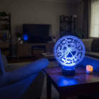 Rozsvietena akrylova lampa Mandala s vazkou v modrom svetle na stole